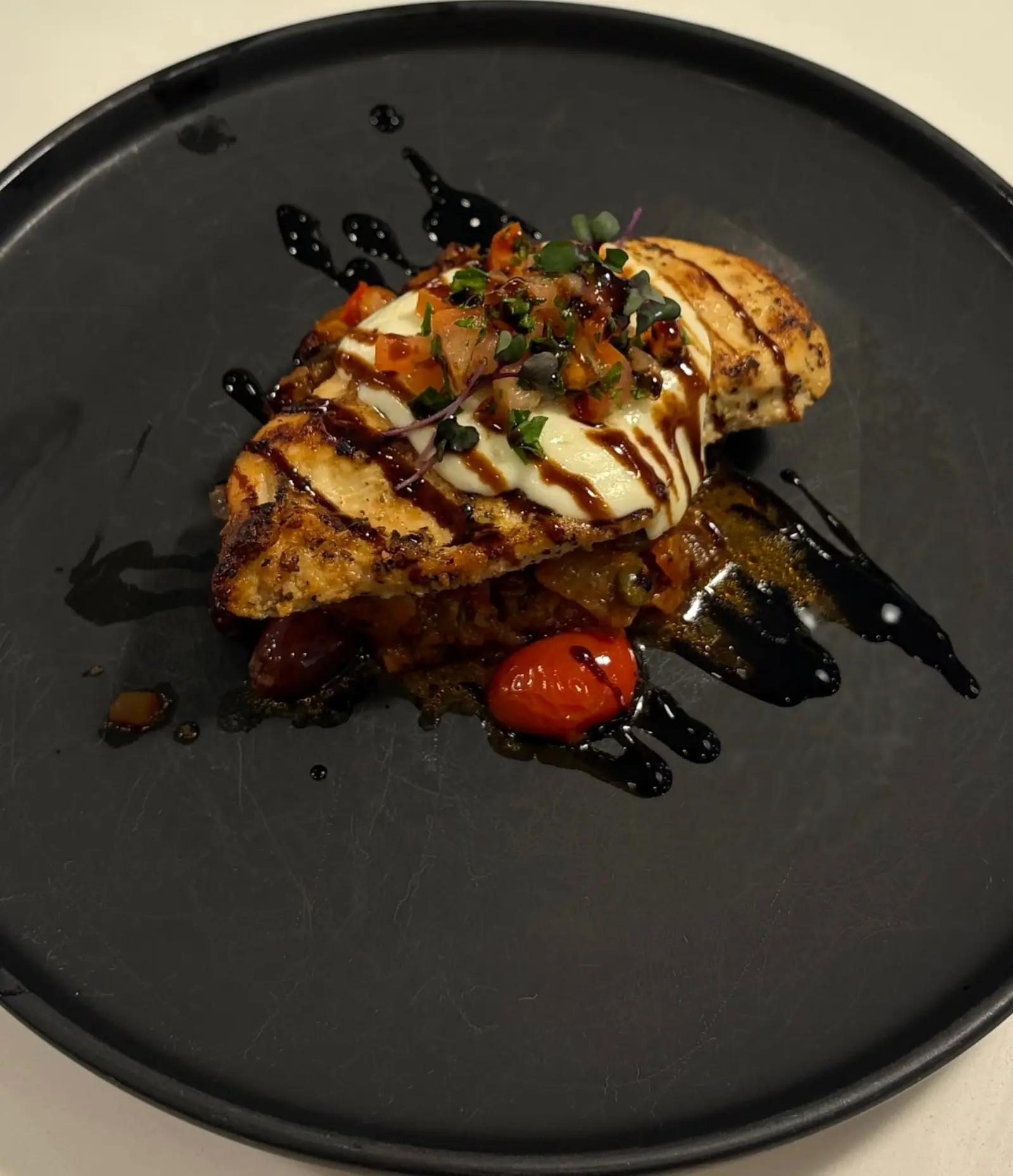 Chicken with vegetables and sauce on a black plate