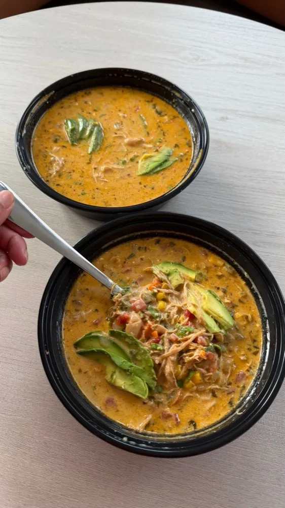 Bowls of chicken soup topped with avocado